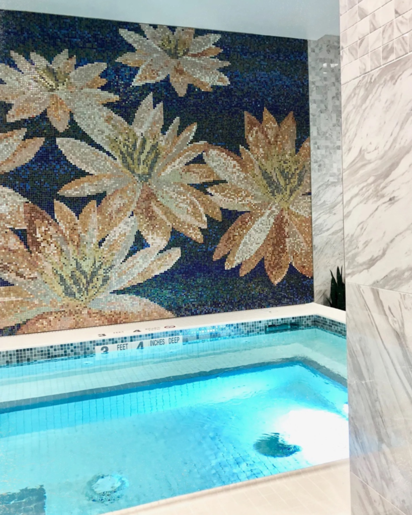 A pool at the wellness center, showing mosaic tiles next to water.