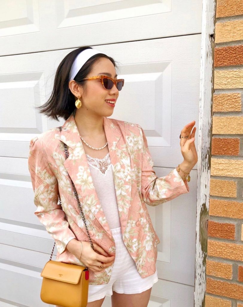 Girl wearing a vintage peach floral blazer, yellow handbag, sunglasses, and white headband.