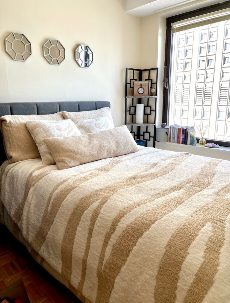 A full size bed with a Sunday Citizen Woodland Comforter and pillows in a New York City bedroom.