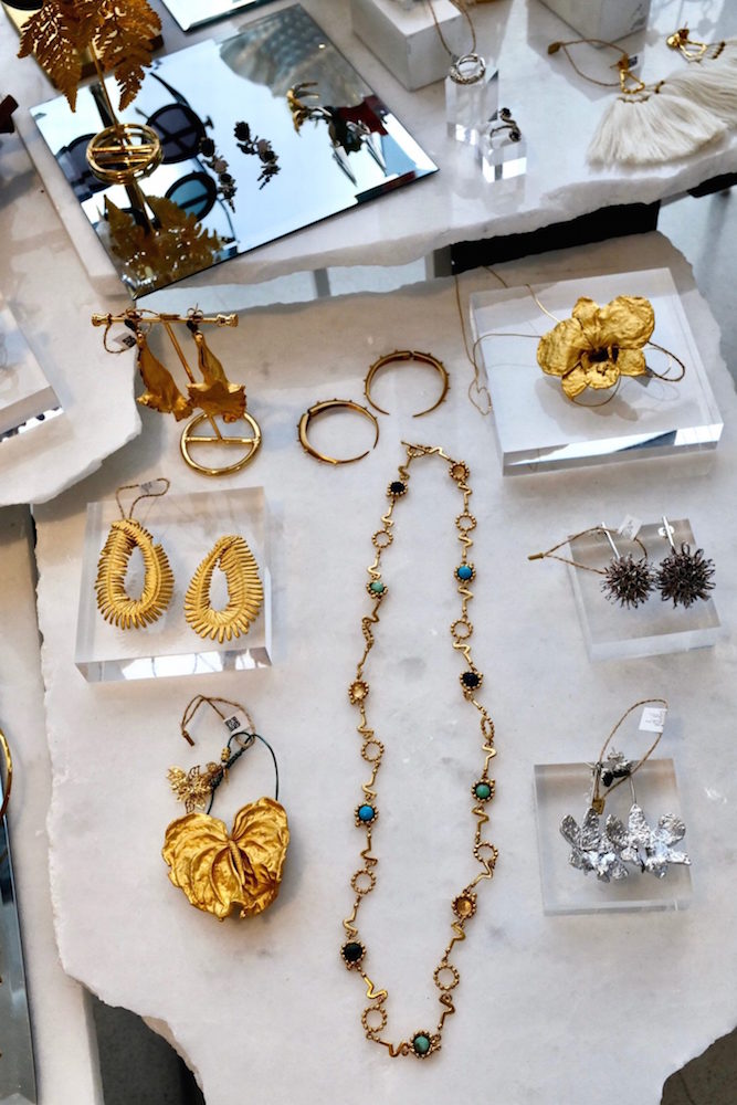 Gold necklaces and earrings on a white marble table by Aysha Bilgrami for El Dorado Art.