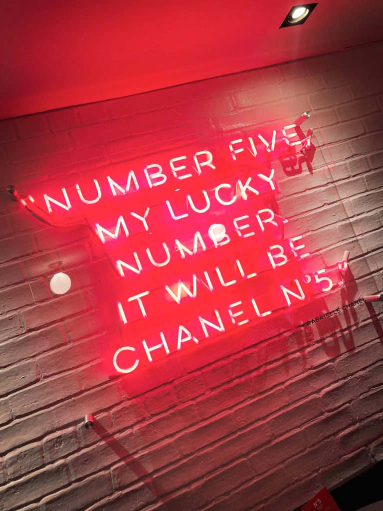 A red neon sign that reads, "Number Five my lucky number it will be Chanel No. 5" Gabrielle Chanel.