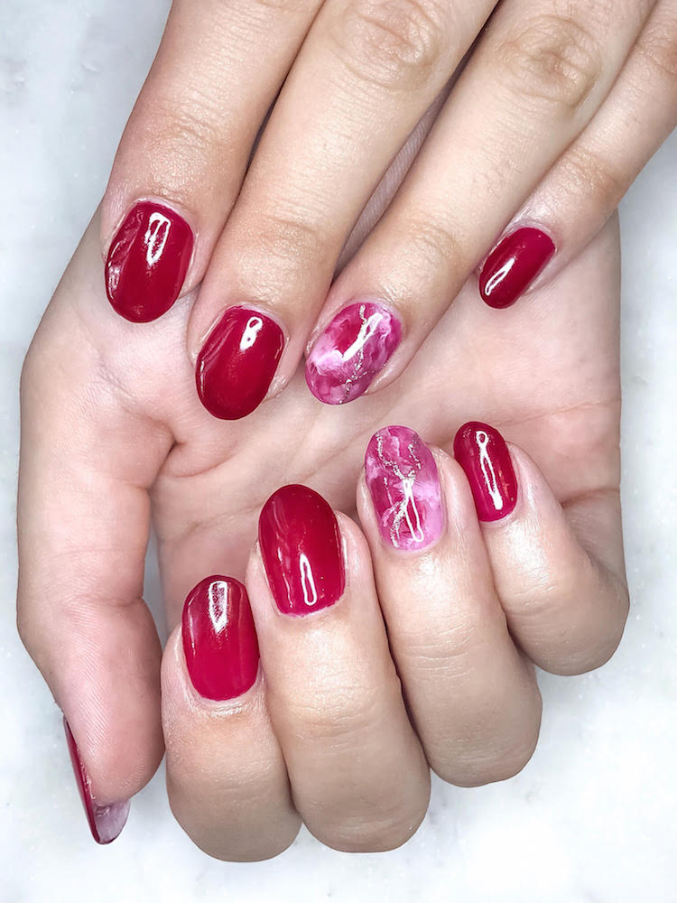 Two hands with shiny red nails by VW nail bar at the Leafgel seminar.