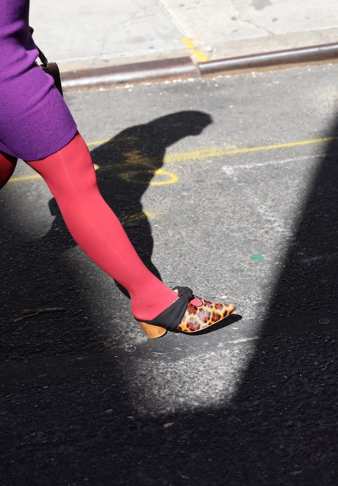A leg in red L'egg tights and leopard print shoes on a concrete floor.