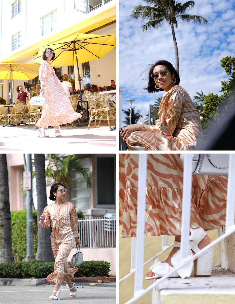 Wendy Sy outside wearing a orange zebra printed dress with white sandals among palm trees in Miami.