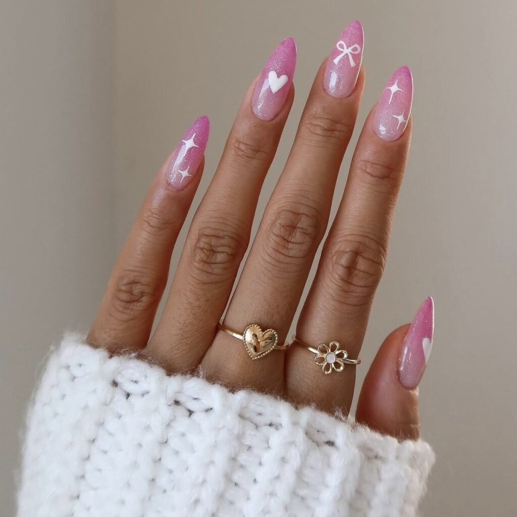 pink hearts and bow nails with a white sweater sleeve and beige background.