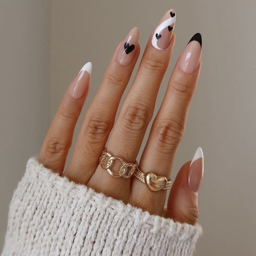 french manicure with black hearts and a white swirl design on the middle finger.