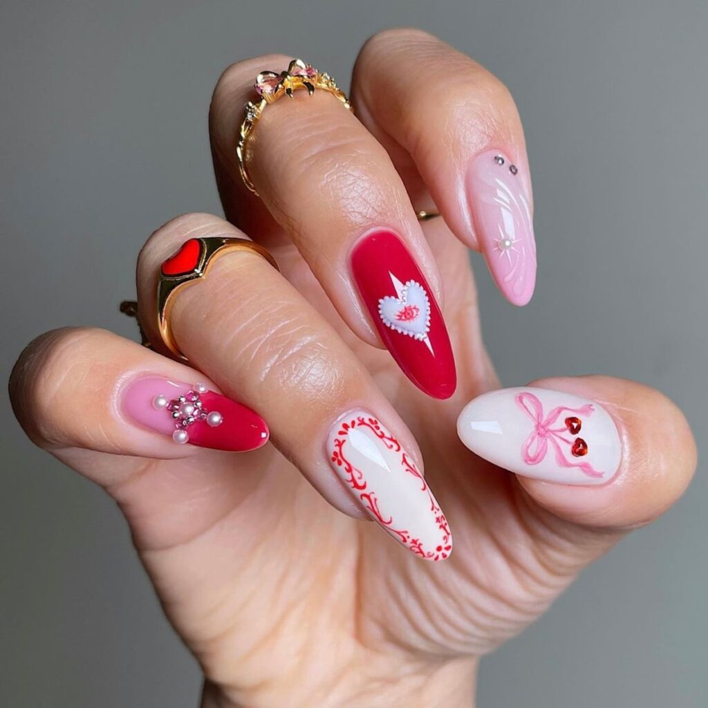 valentines day manicure with pink and red designs including a bow, heart, and pearls.