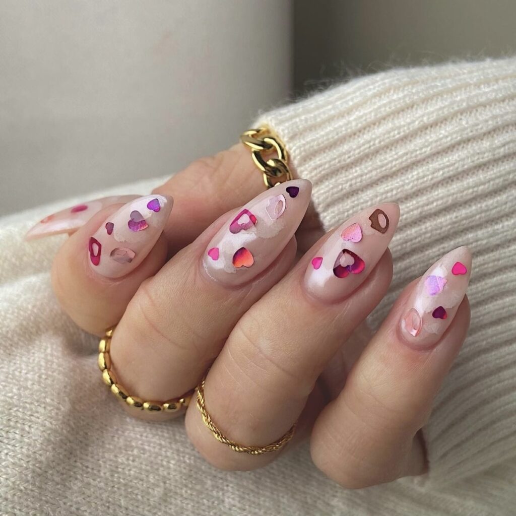 Hand with pink nails and glitter sparkle designs with a cream sweater.