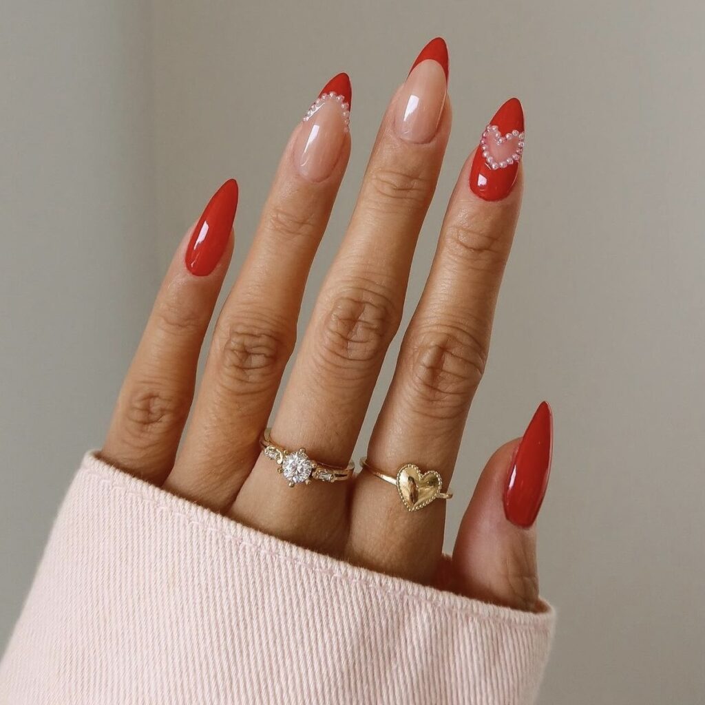 red manicure with pearl embellishments and red french tips on the middle and ring fingers.