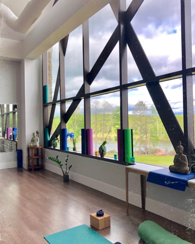 Yoga room with yoga mats at the wellness center, YO1 Health Resort, with a large window view of grassland and blue sky.