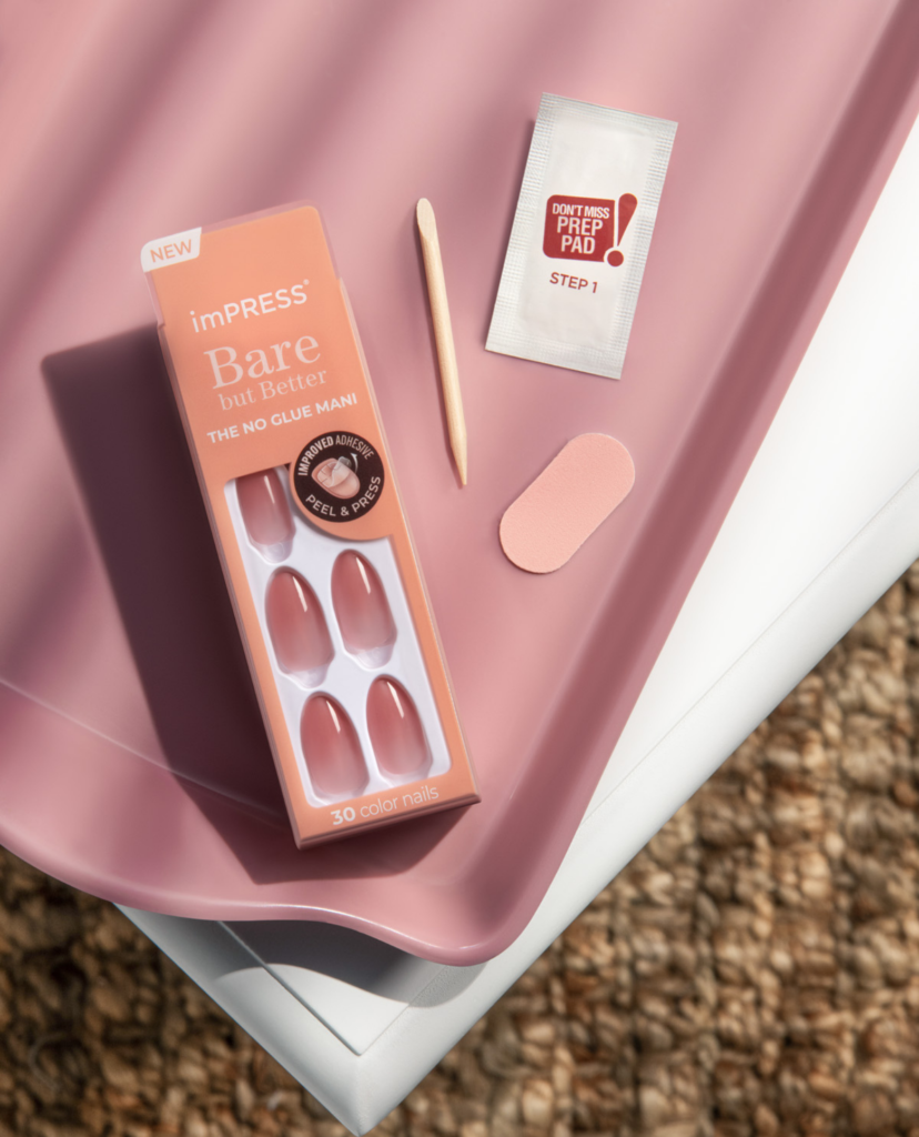 A package of almond shape pink press-on nails on a white table