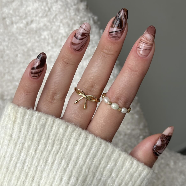 A hand with brown swirl espresso nails