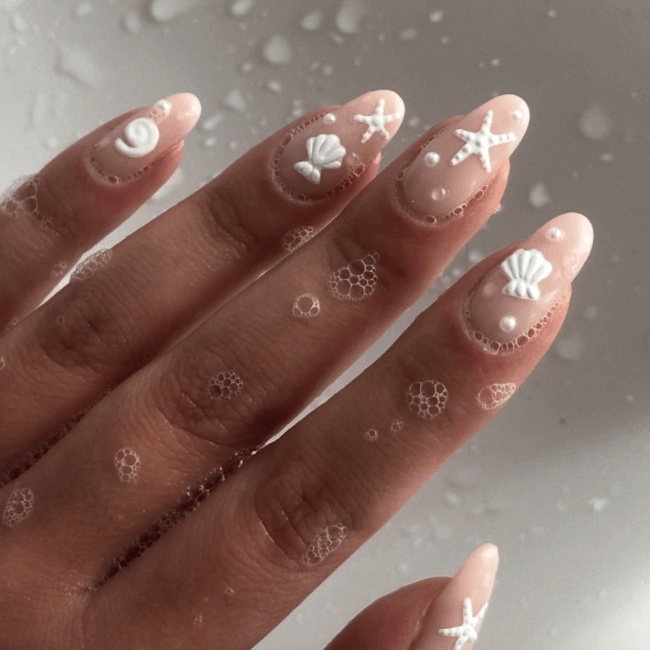 One hand with white seashell manicure and bubbles all around, inspiration for soap nails.