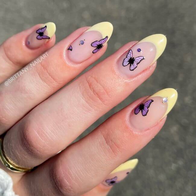 One of the most elegant nail designs 2026, featuring butter yellow French tips with purple butterfly art