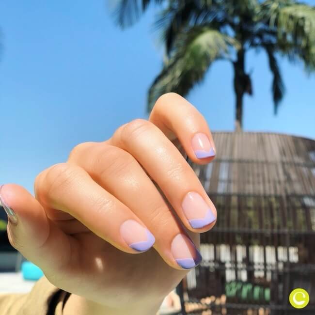 A hand showing a short-length French manicure with light purple tips