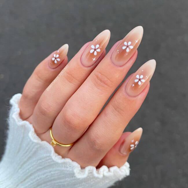 Long nails with am ombre brown shade and a white flower in the middle