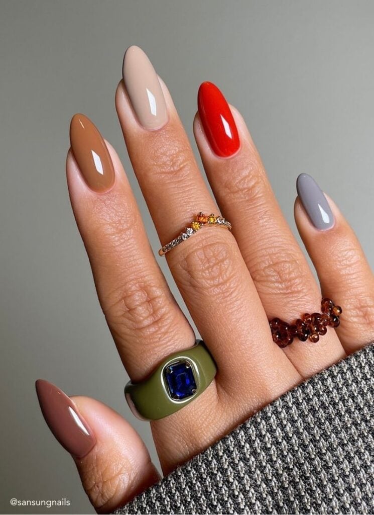 fall nails in various gem tones on a gray background