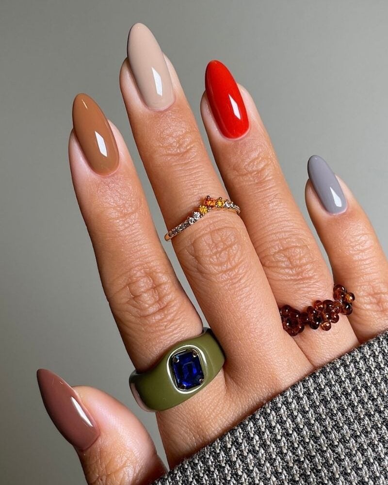 fall nails in various gem tones on a gray background