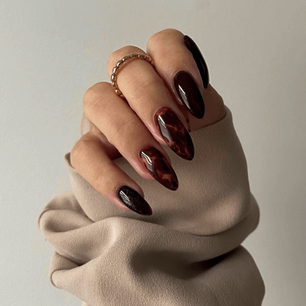A hand with tortoise nails with a beige sleeve
