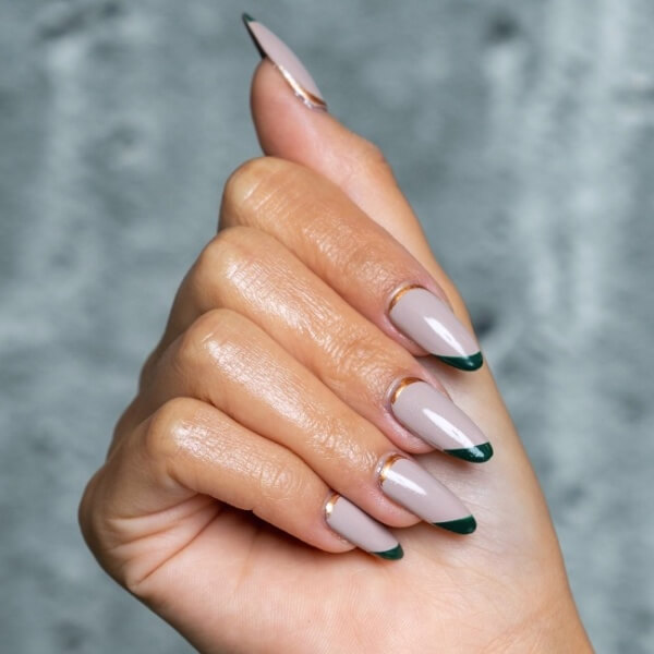 A hand with a neutral manicure with dark green details