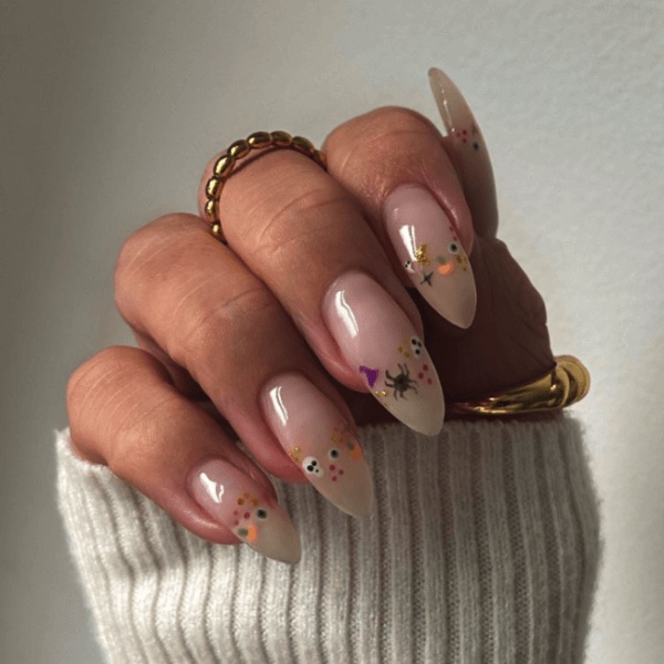 A hand with Halloween nail designs and a cream sweater sleeve