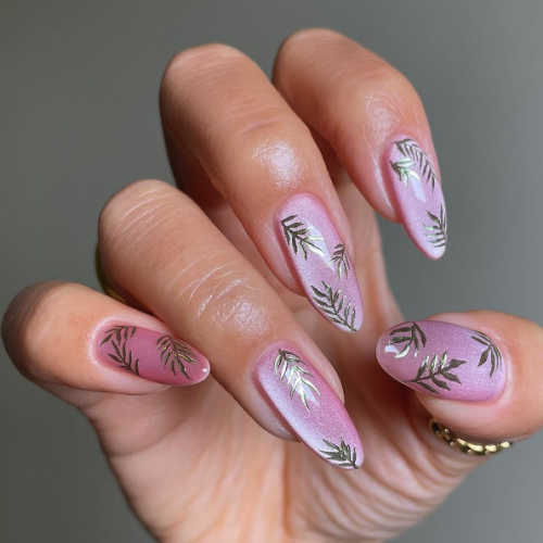 pink nail art with gold leave designs and a gray background.