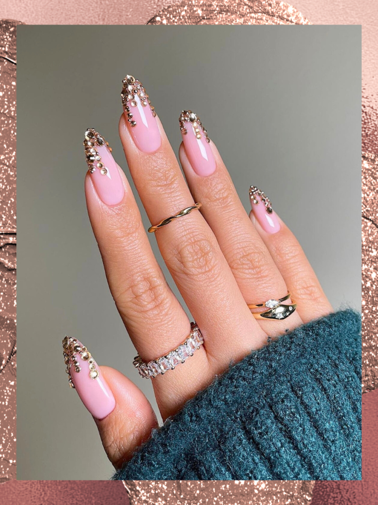 Close up of rose gold nails wth pink rhinestone embellishments on the tips.
