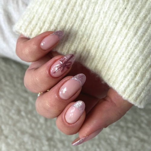 Close up of rose gold nails with glitter tips and a white sweater sleeve.