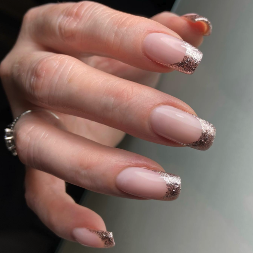 long square shaped nails with a pink base and glitter tips.