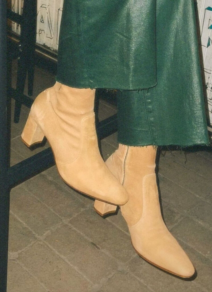 Beige block heel shoes with dark green pants.