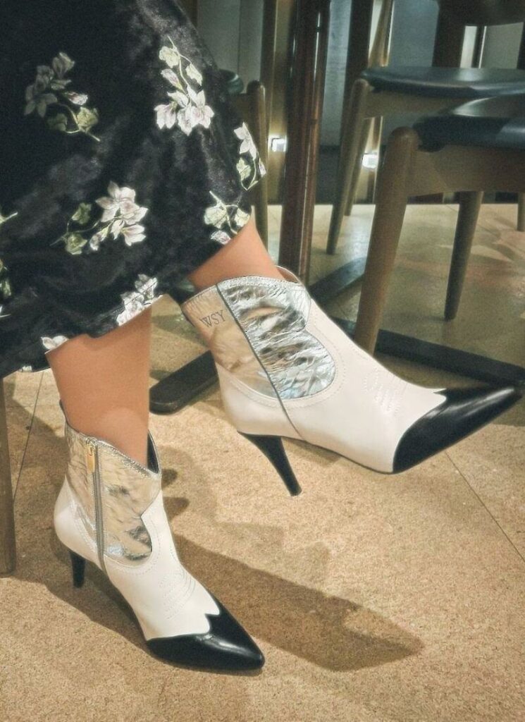Black and white cowboy boots with a beige background.