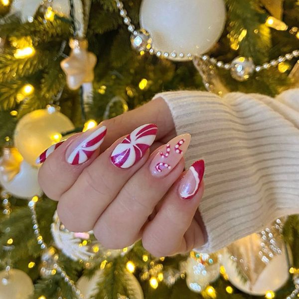 Candy cane nails with a red and white swirl design with a background of a Christmas tree