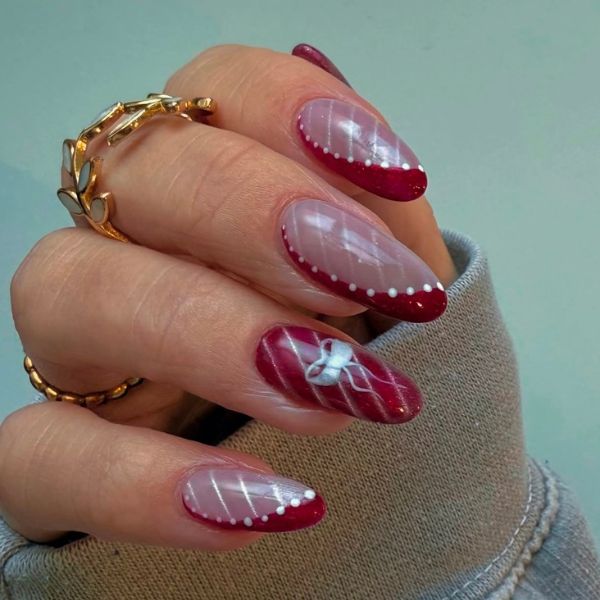 new year nails with dark red stripe designs and a bow on the ring finger.