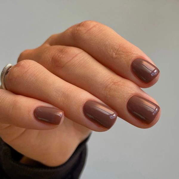 shiny brown manicure on a gray background.