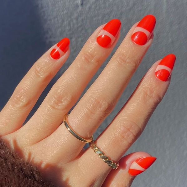 One hand with red negative space nails with a gray background.