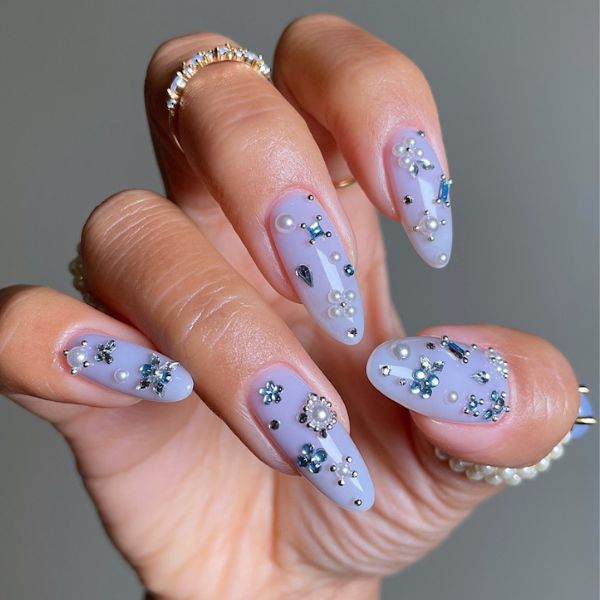cool blue nails with sparkle embellishments on a gray background.