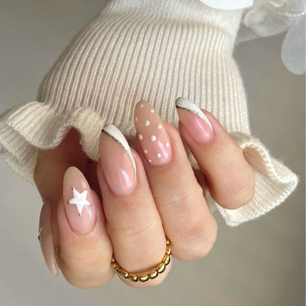 white winter nails with a star and polka dot design on a beige background.