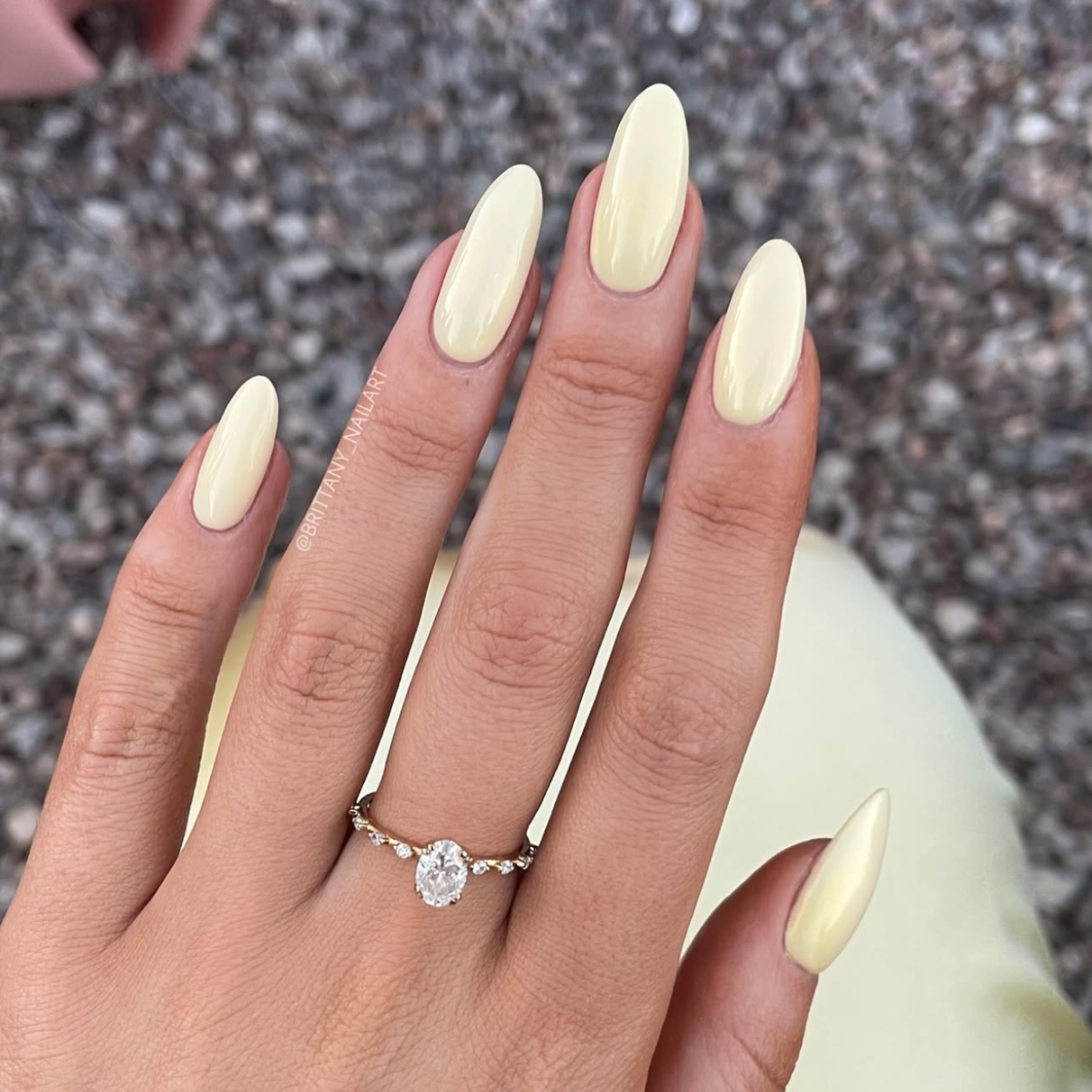 Close-up of butter yellow nails with a gray background.