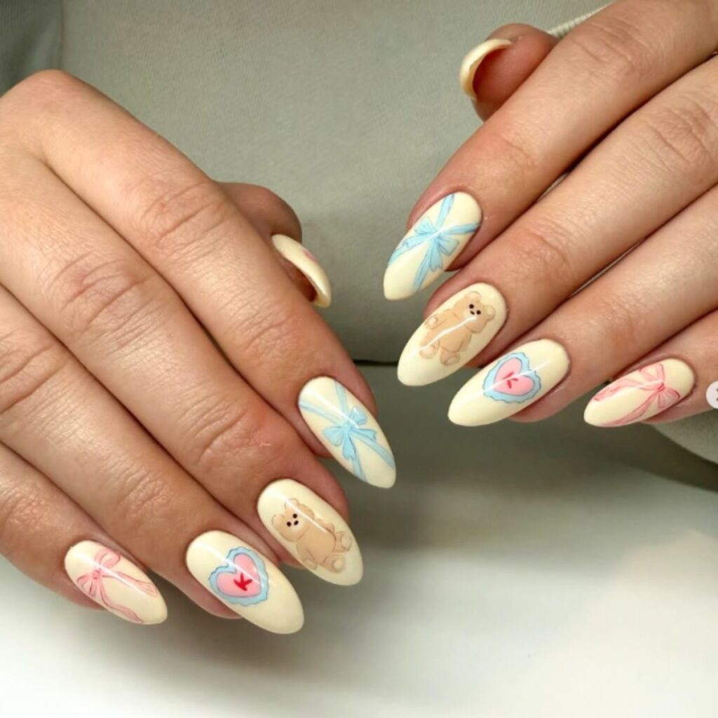Spring nails with a cream base, designs featuring teddy bears, hearts, and bows, on a white background.