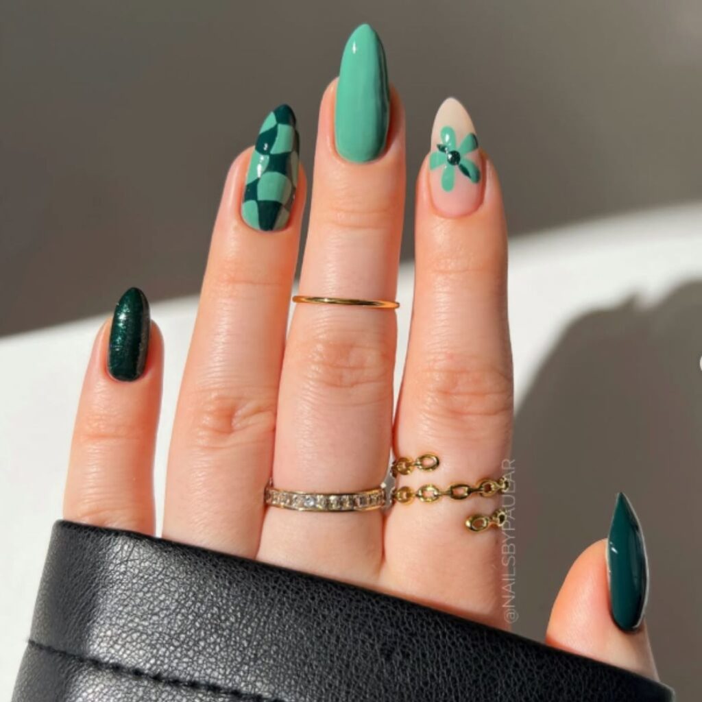 Green nails with a checker and flower design and a white background with shadows.