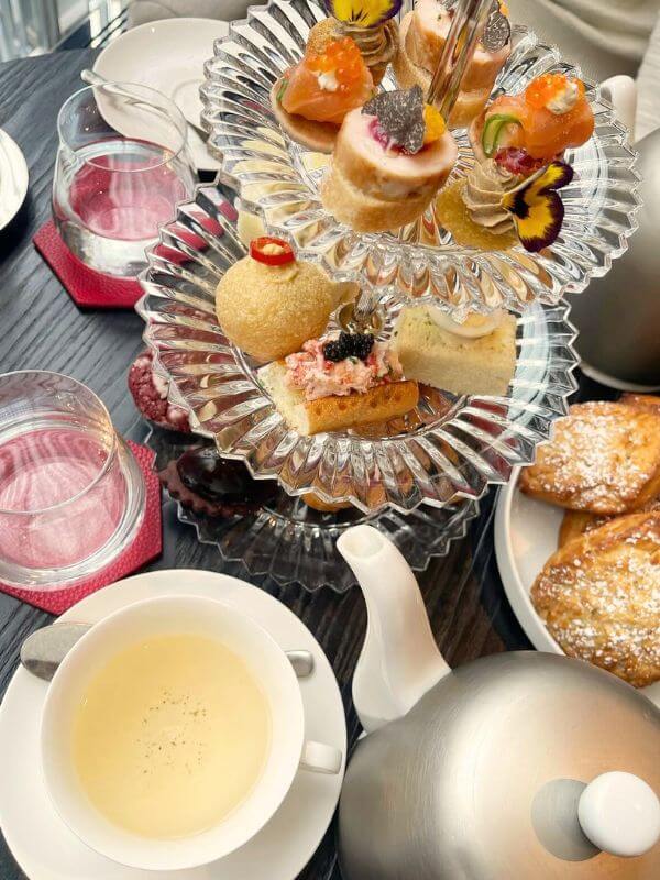 Three-tier glass tray with pastries and a tea pot at the Baccarat Hotel Grand Salon, one of the best afternoon tea in nyc spots.
