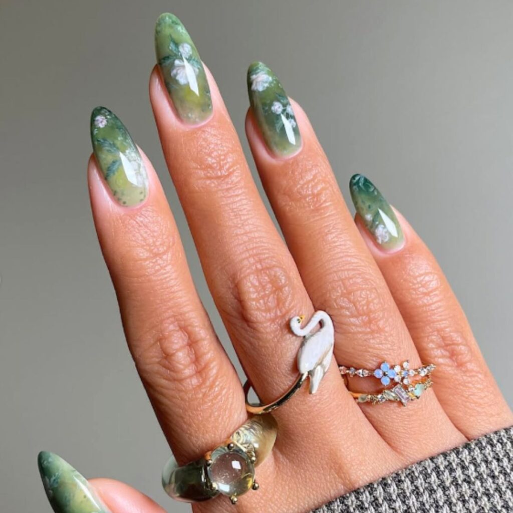 Light green spring nails with swan and flower rings on a gray background.