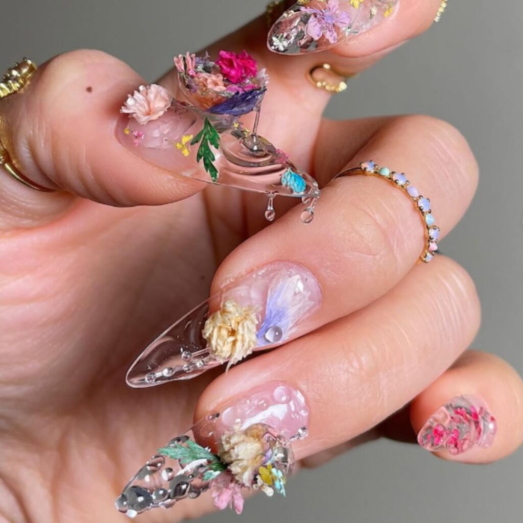 Colorful floral design long spring nails with a gray background.