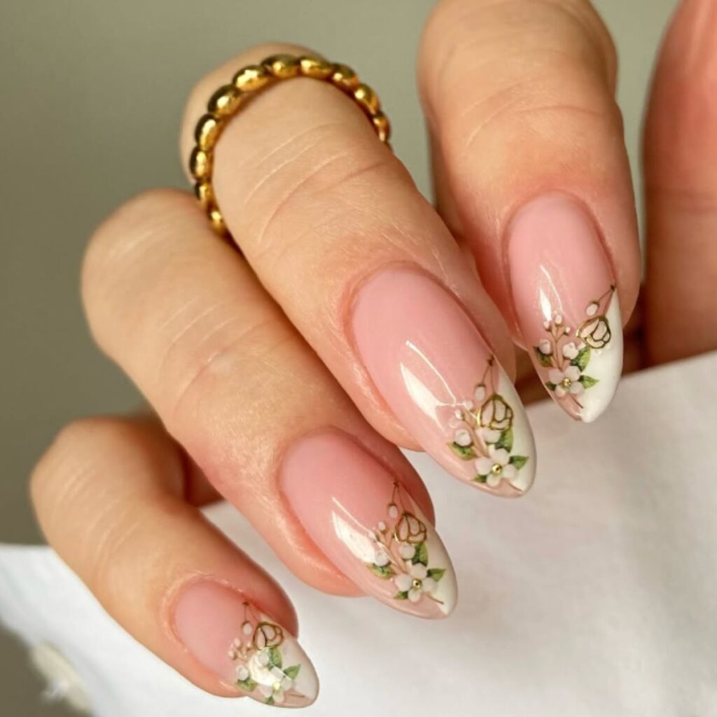 A close-up of spring nails designs with dainty white and green flowers and a white sleeve on a light green background.