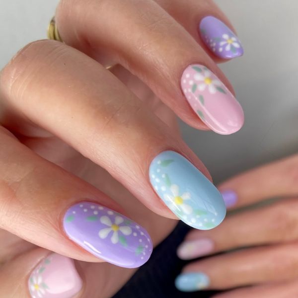 Colorful pastel manicure with floral details on a gray background.