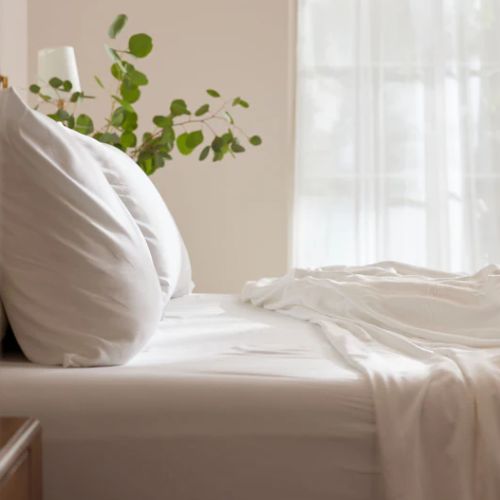Close-up of white bed sheets adding warmth and comfort to a cozy home.
