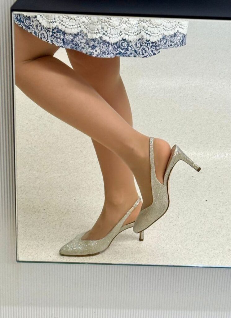 Close-up mirror photo of silver mid-heel slingbacks, stylish summer shoes 2025.