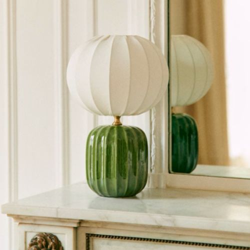 Stylish table lamp with a green base gentle light in a peaceful bedroom corner.
