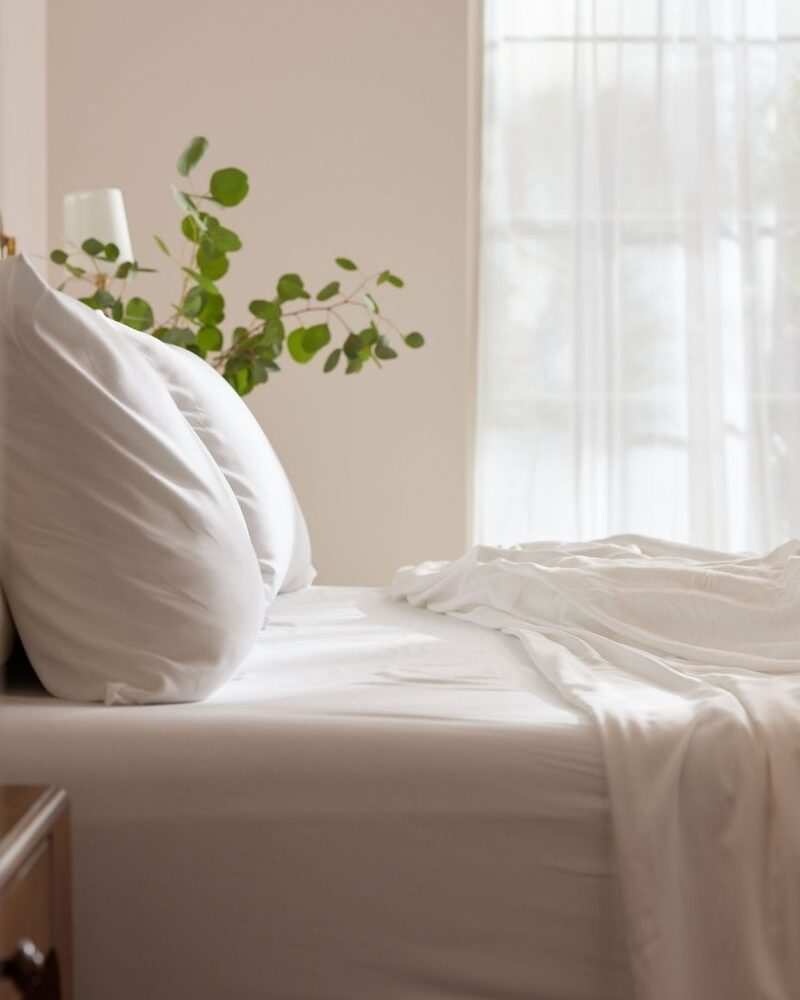 A calming scene of a bed with bamboo sheets for a post on Cozy Earth Sheets review with a promo code.