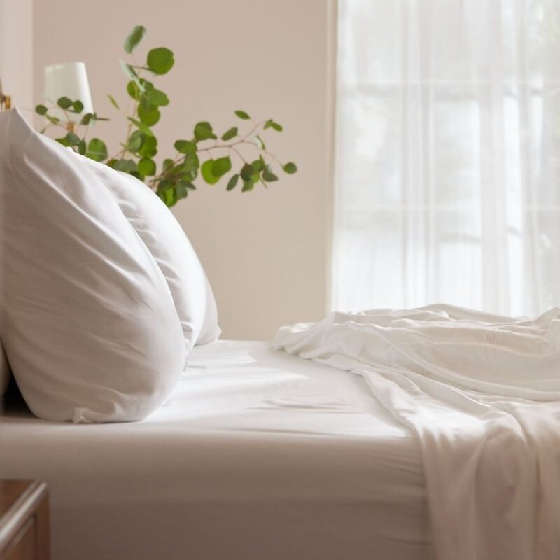 A calming scene of a bed with bamboo sheets for a post on Cozy Earth Sheets review with a promo code.